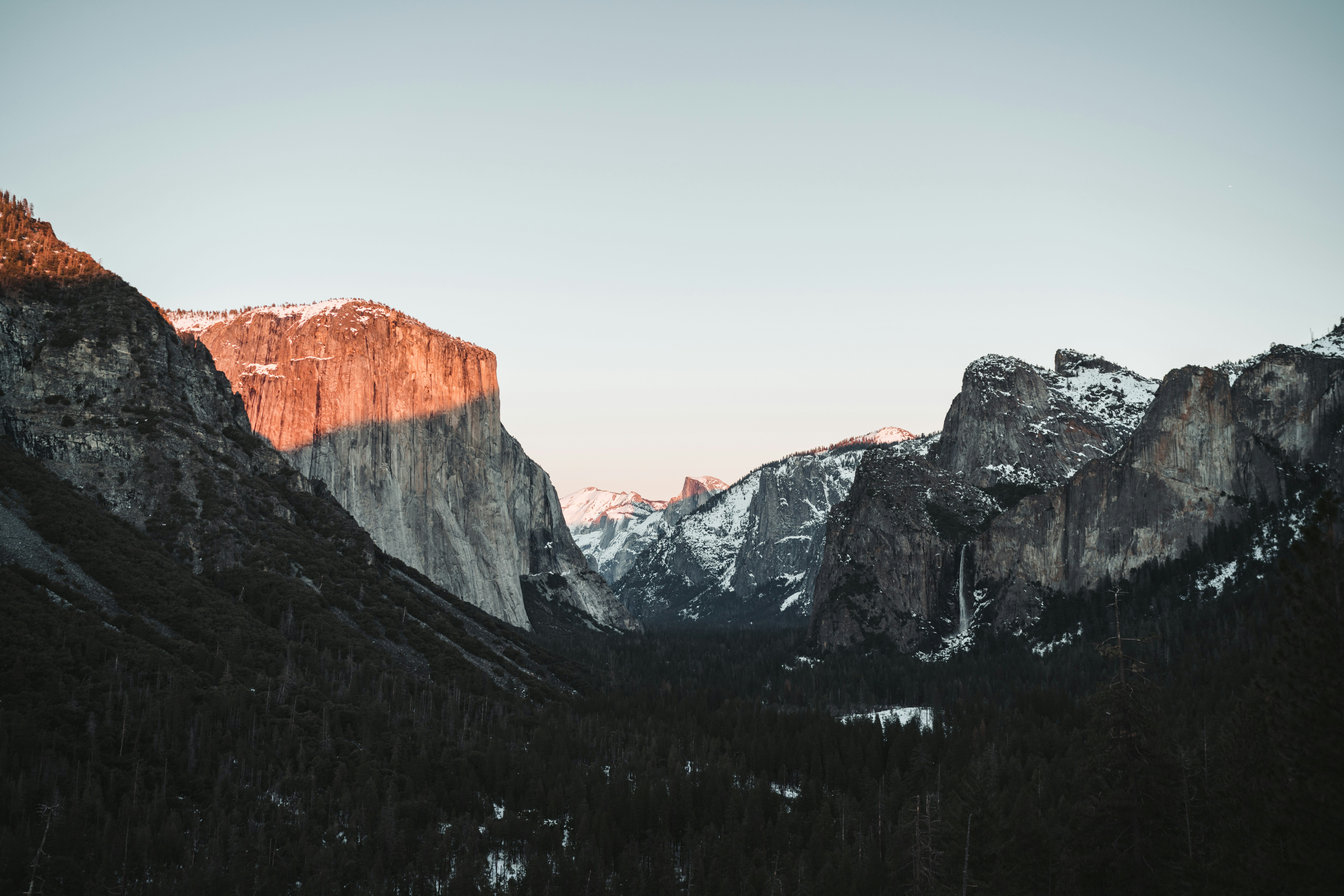 the mountains are covered in snow and trees, 