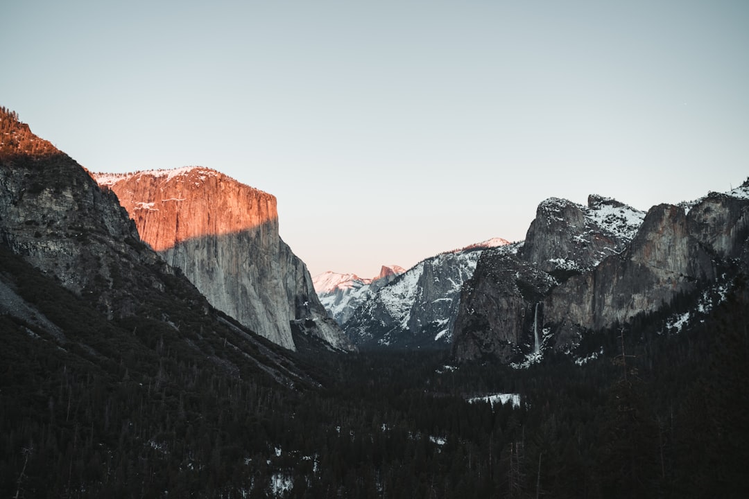 the mountains are covered in snow and trees,