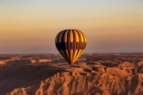 A colorful hot air balloon floating over a vast desert landscape at dawn.