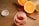 A jar filled with colorful gummy vitamins is placed on a wooden table. The jar is open, with the cap lying beside it. In the background, there is a wooden cutting board with halved oranges, a lemon, and a lime, adding a vibrant touch to the scene.