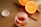 A jar filled with colorful gummy vitamins is placed on a wooden table. The jar is open, with the cap lying beside it. In the background, there is a wooden cutting board with halved oranges, a lemon, and a lime, adding a vibrant touch to the scene.