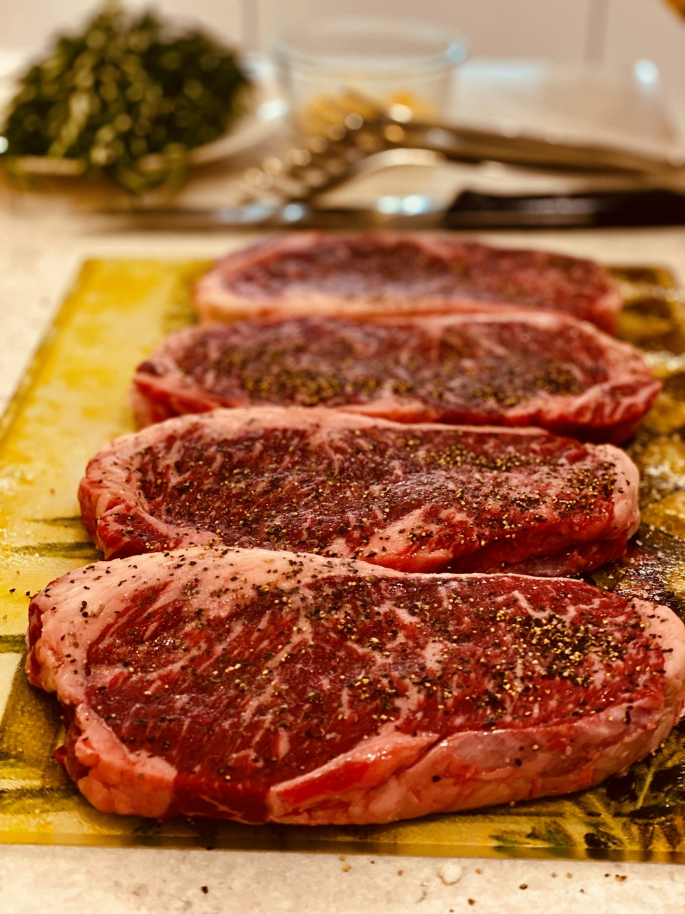 three raw steaks sit on a cutting board