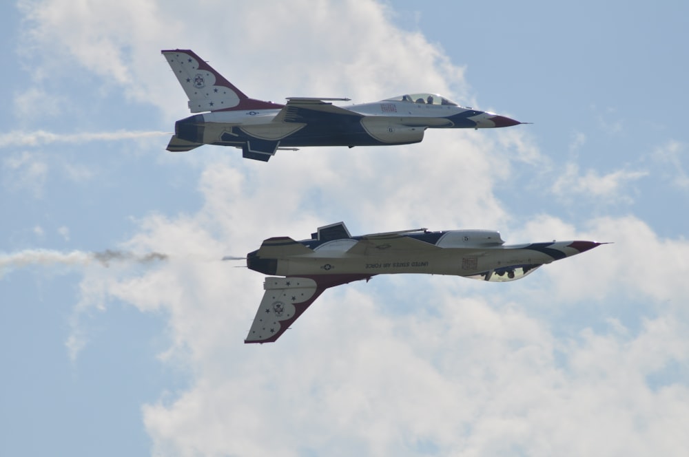 two jets flying in the sky with smoke coming out of them