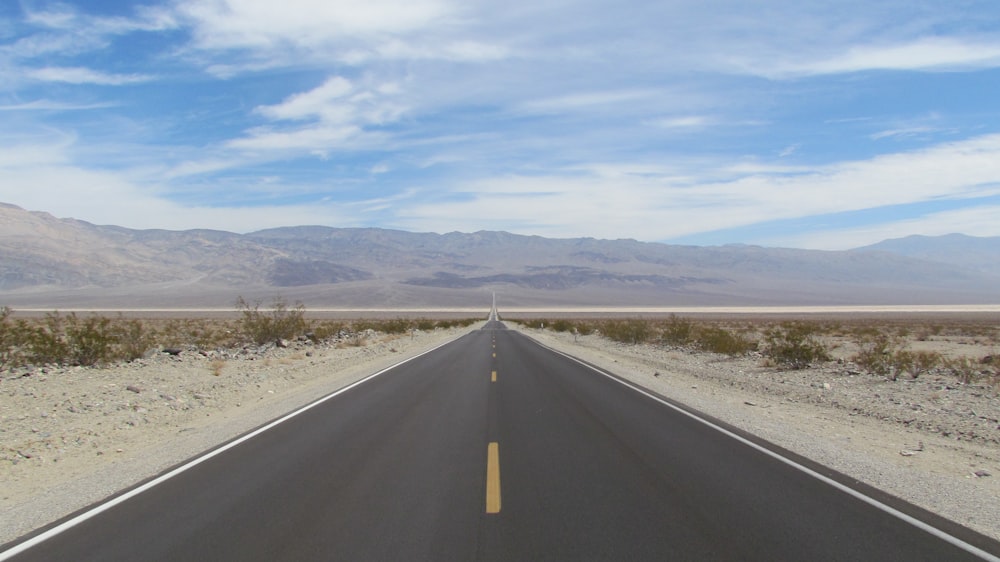 a long empty road with mountains in the background