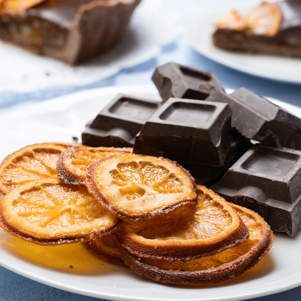 a white plate topped with slices of orange next to chocolate