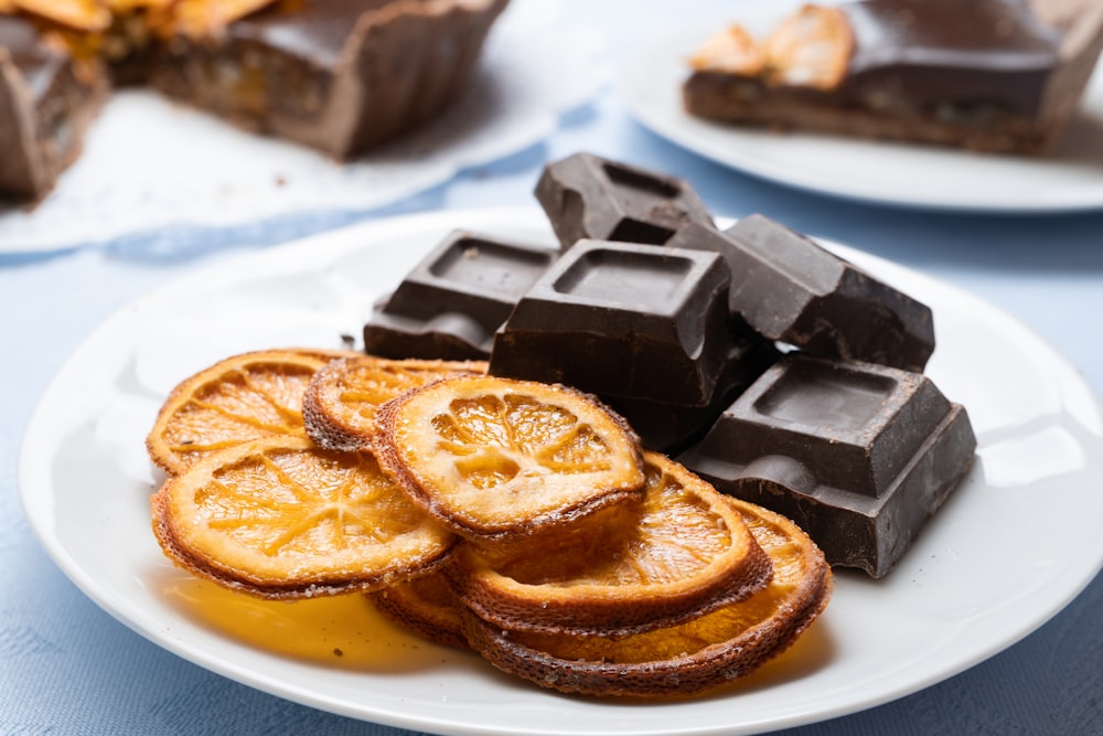 a white plate topped with slices of orange next to chocolate