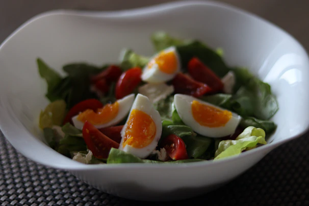 A protein-rich salad with boiled eggs, spinach, walnuts, and a light vinaigrette in a rustic bowl.
