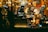 A cluttered shop window filled with a variety of vintage and eclectic items, including lamps, statues, and old mechanical devices. The display is densely packed, creating an antique and nostalgic atmosphere with warm lighting.