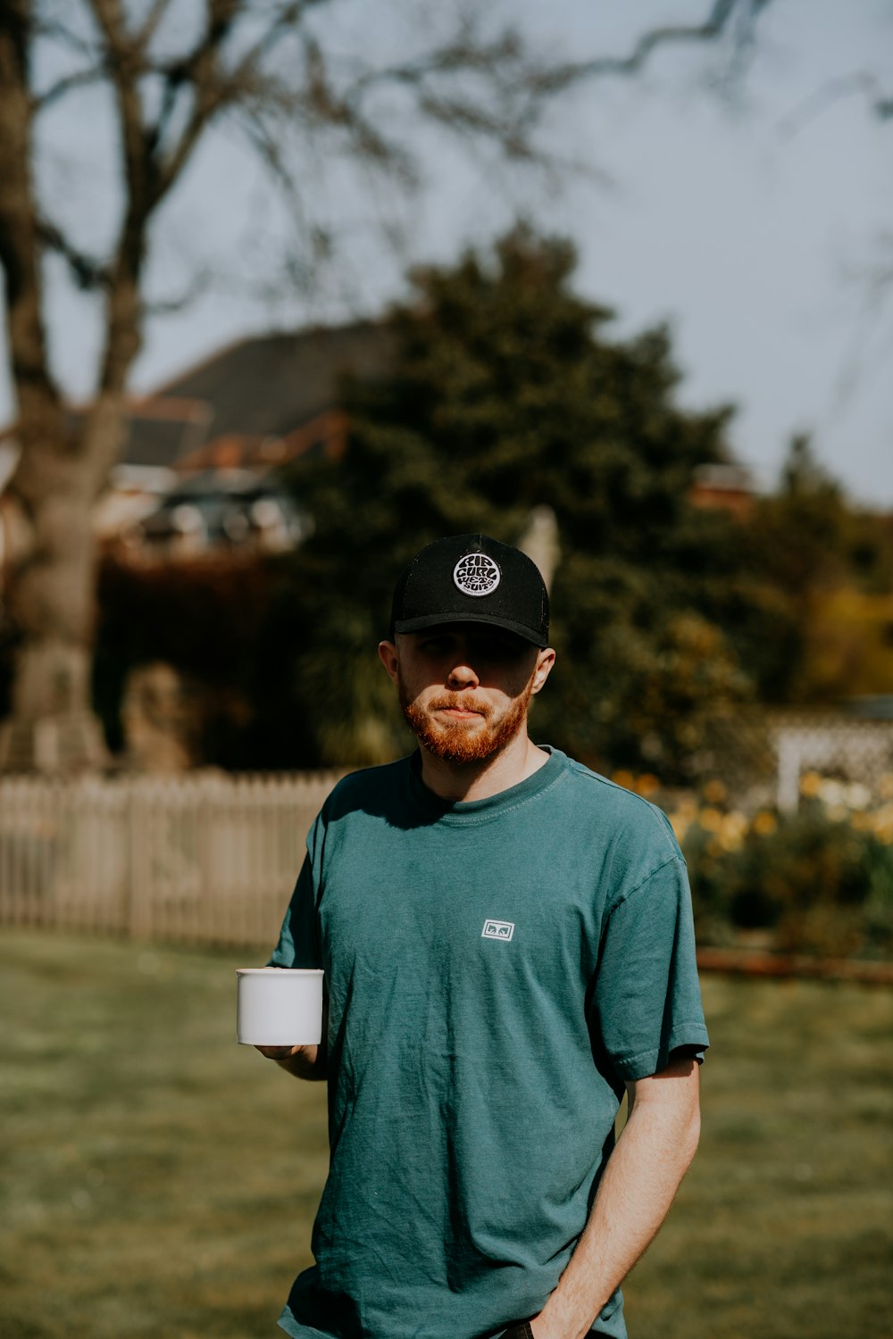 a man standing in a yard holding a cup of coffee