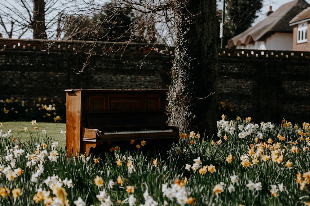 a piano sitting in the middle of a field of flowers