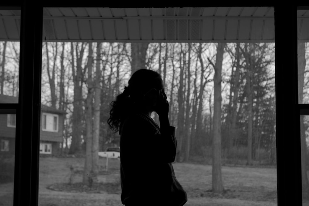 a woman standing in front of a window talking on a cell phone