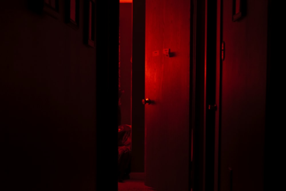a dark hallway with a red light coming through the doors