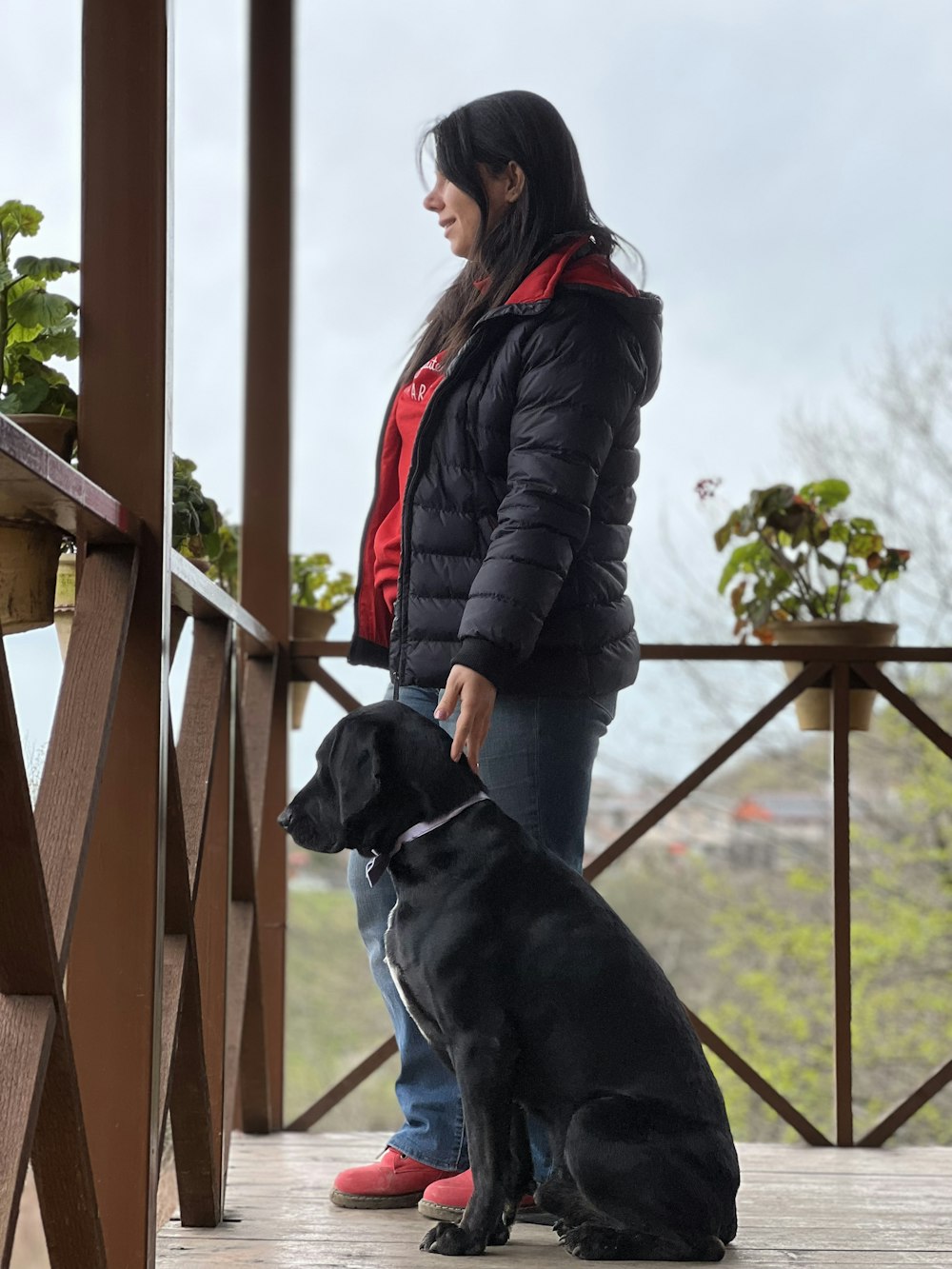 a woman standing next to a black dog