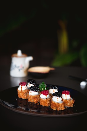 a black plate topped with small desserts on top of a table