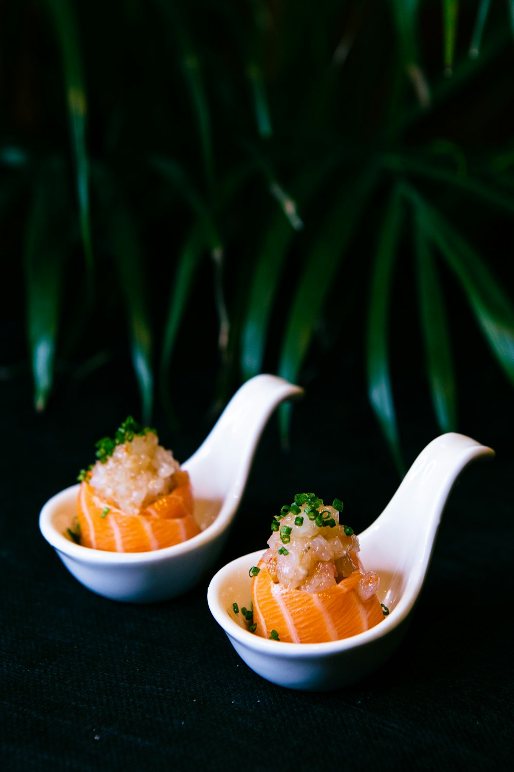 a couple of white spoons filled with food on top of a table