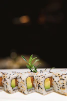 Close-up of a vibrant sushi roll with fresh avocado and spicy mayo drizzle.