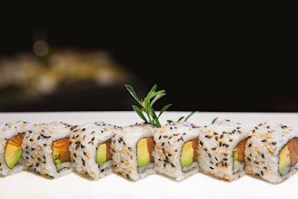 Elegant sushi rolls arranged on a dark slate plate with vibrant slices of fish and avocado.
