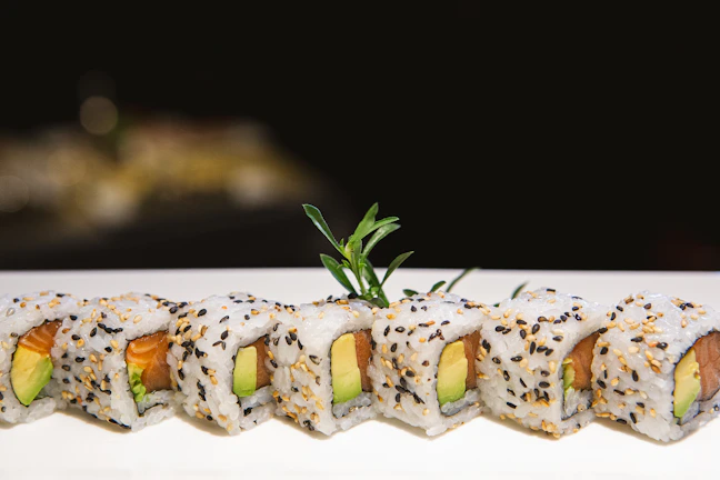 Close-up of a vibrant sushi roll with fresh avocado and salmon, artfully plated.