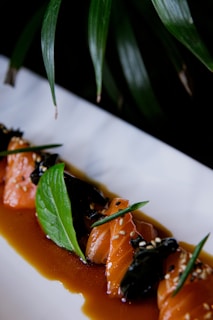 Elegant plating of seared salmon topped with ginger-infused glaze and microgreens on a dark ceramic plate