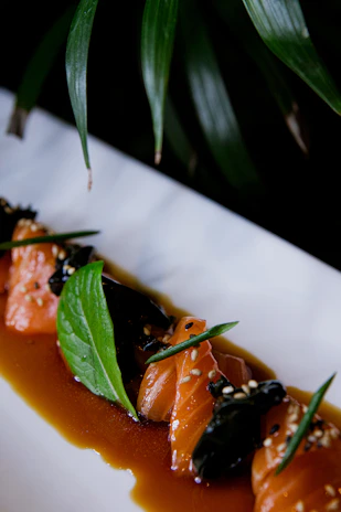 An elegant serving of grilled salmon glazed with a sweet soy sauce, garnished with sesame seeds.