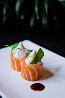 a white plate topped with sushi covered in sauce