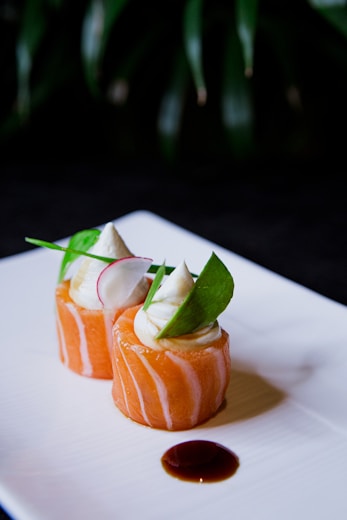 a white plate topped with sushi covered in sauce