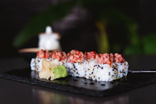 a piece of sushi on a black plate