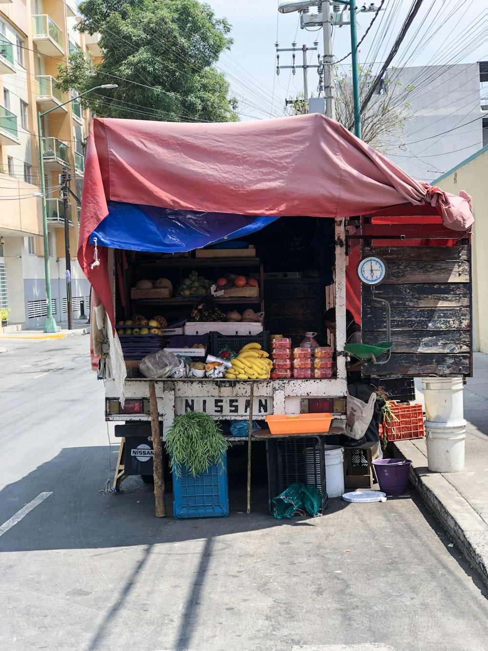 a fruit and vegetable stand on the side of the road
