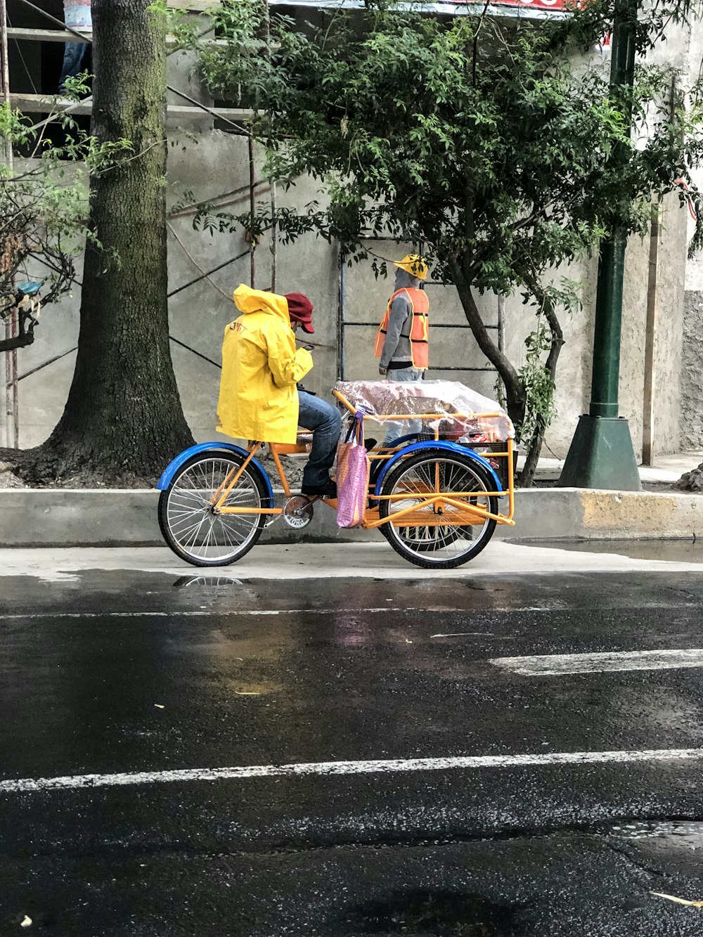 a man riding a bike down a street next to a tree