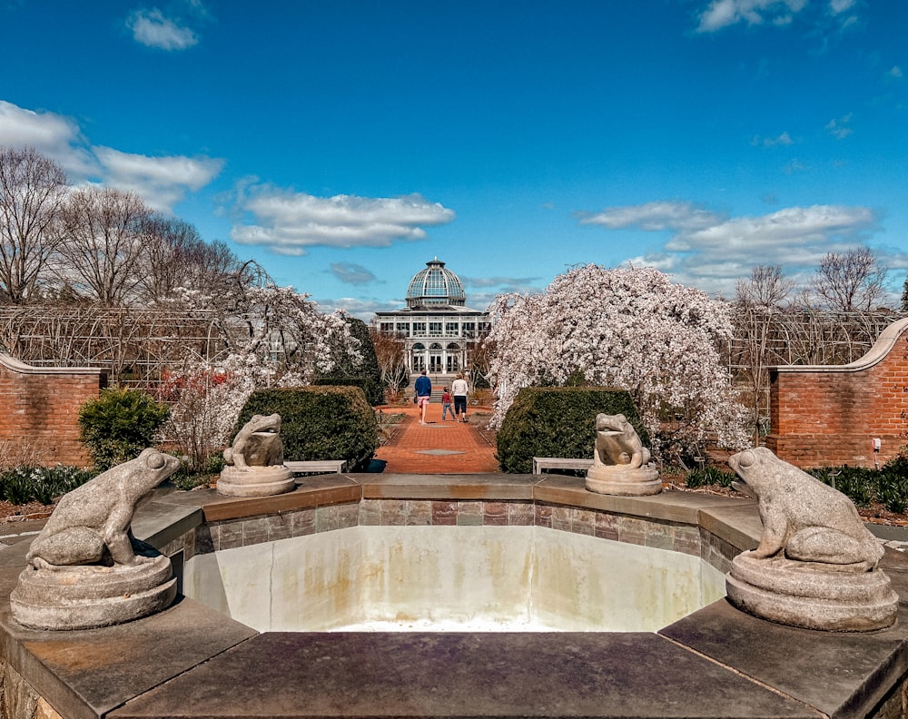 a pond with statues of lions in front of a building