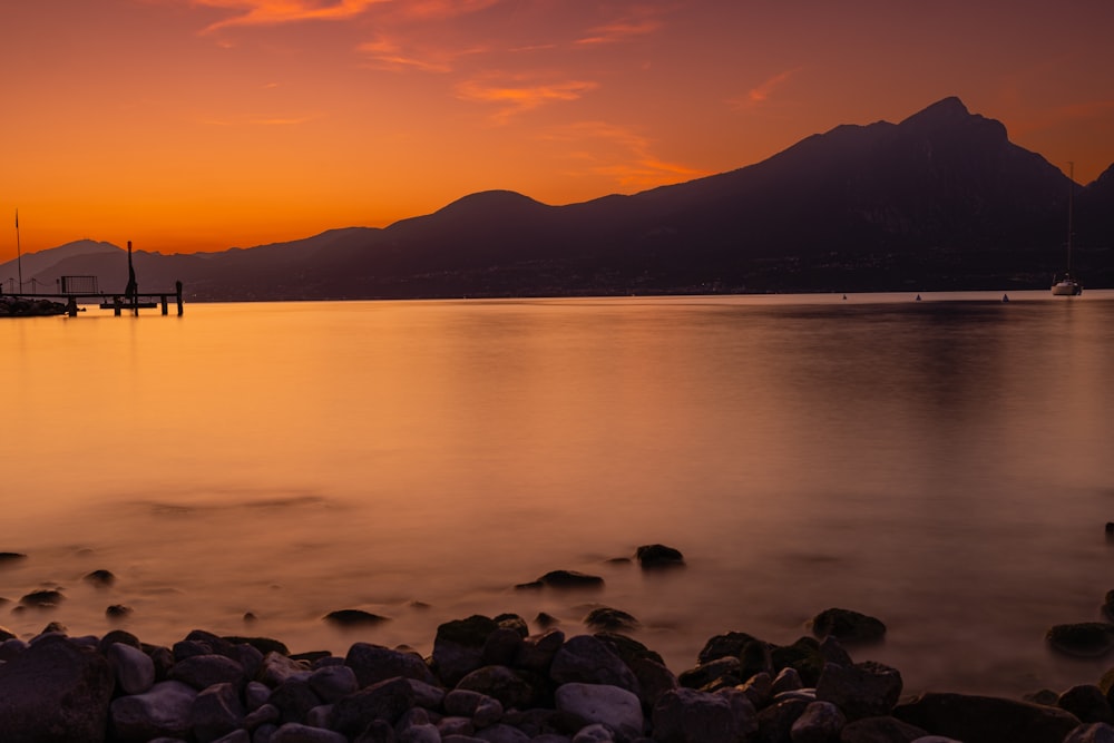 a sunset over a body of water with mountains in the background