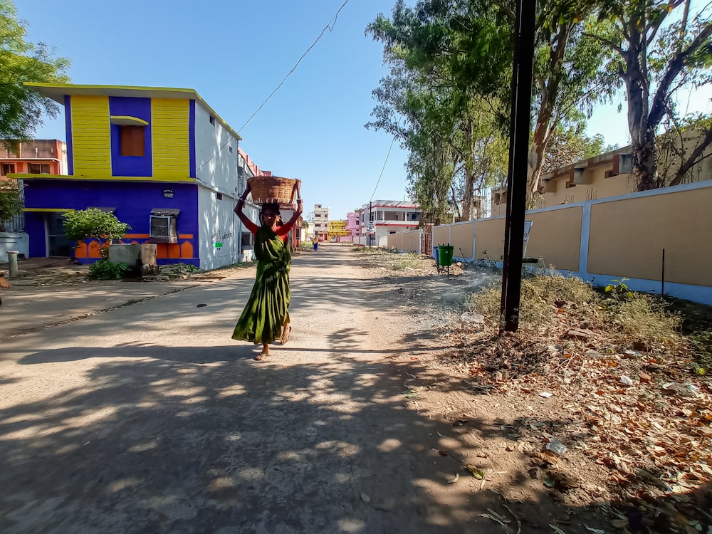 a woman walking down a street carrying a basket on her head