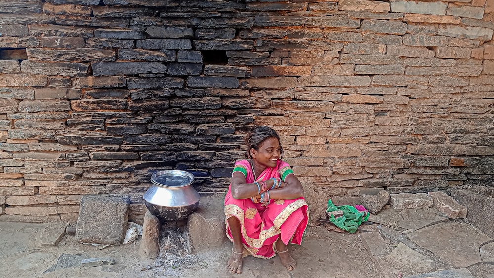 a woman sitting in front of a brick wall