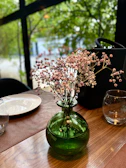 A soft green ceramic vase sitting on a wooden table with fresh wildflowers.
