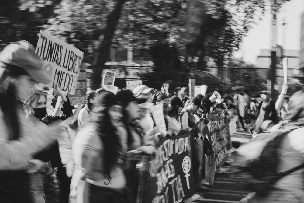 a crowd of people walking down a street holding signs