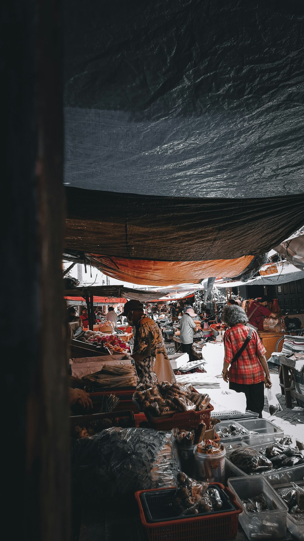 a woman walking through a market with lots of food