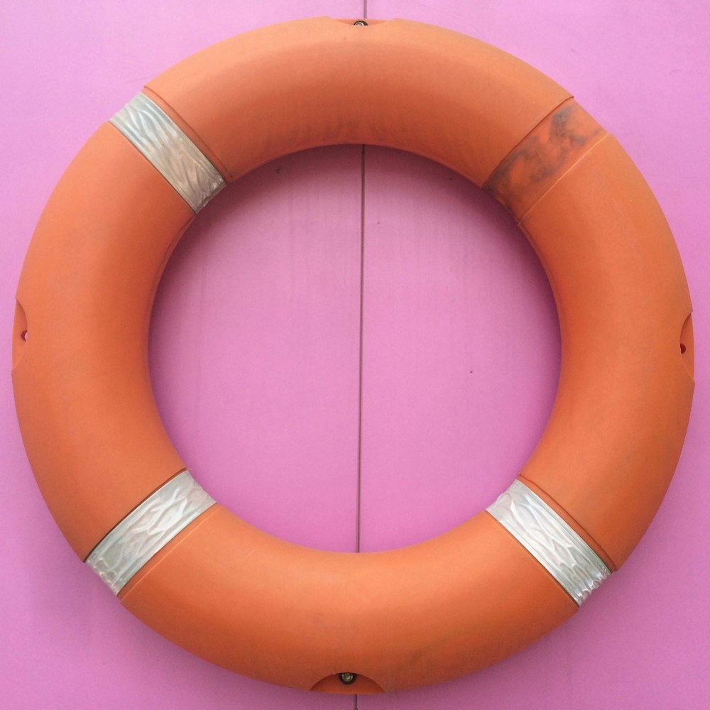 an orange life preserver hanging on a pink wall