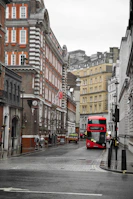 a red double decker bus driving down a city street