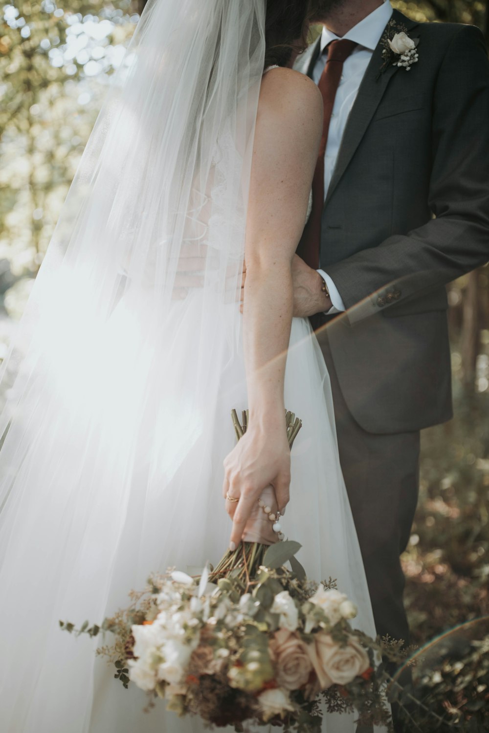 Una sposa e uno sposo con in mano un mazzo di fiori