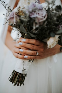 Close-up of manicured hands holding a bouquet of flowers.