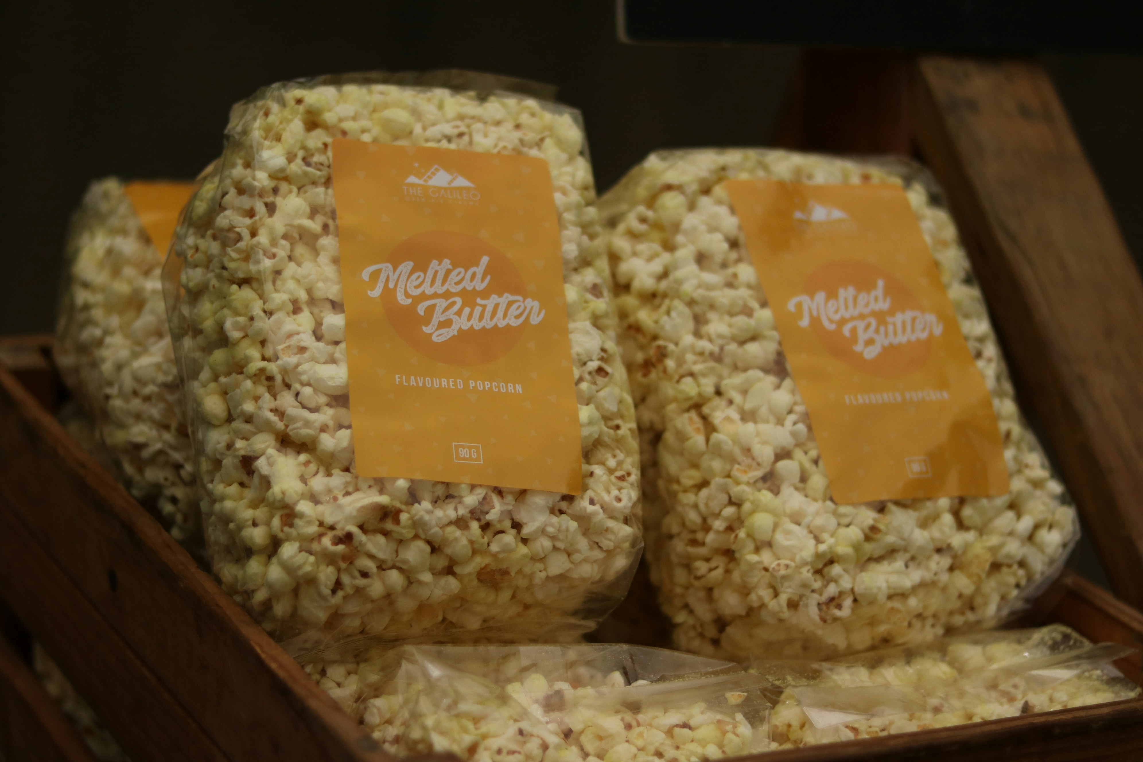 Three bags of gourmet popcorn in caramel, cheese, and butter flavors with festive labels