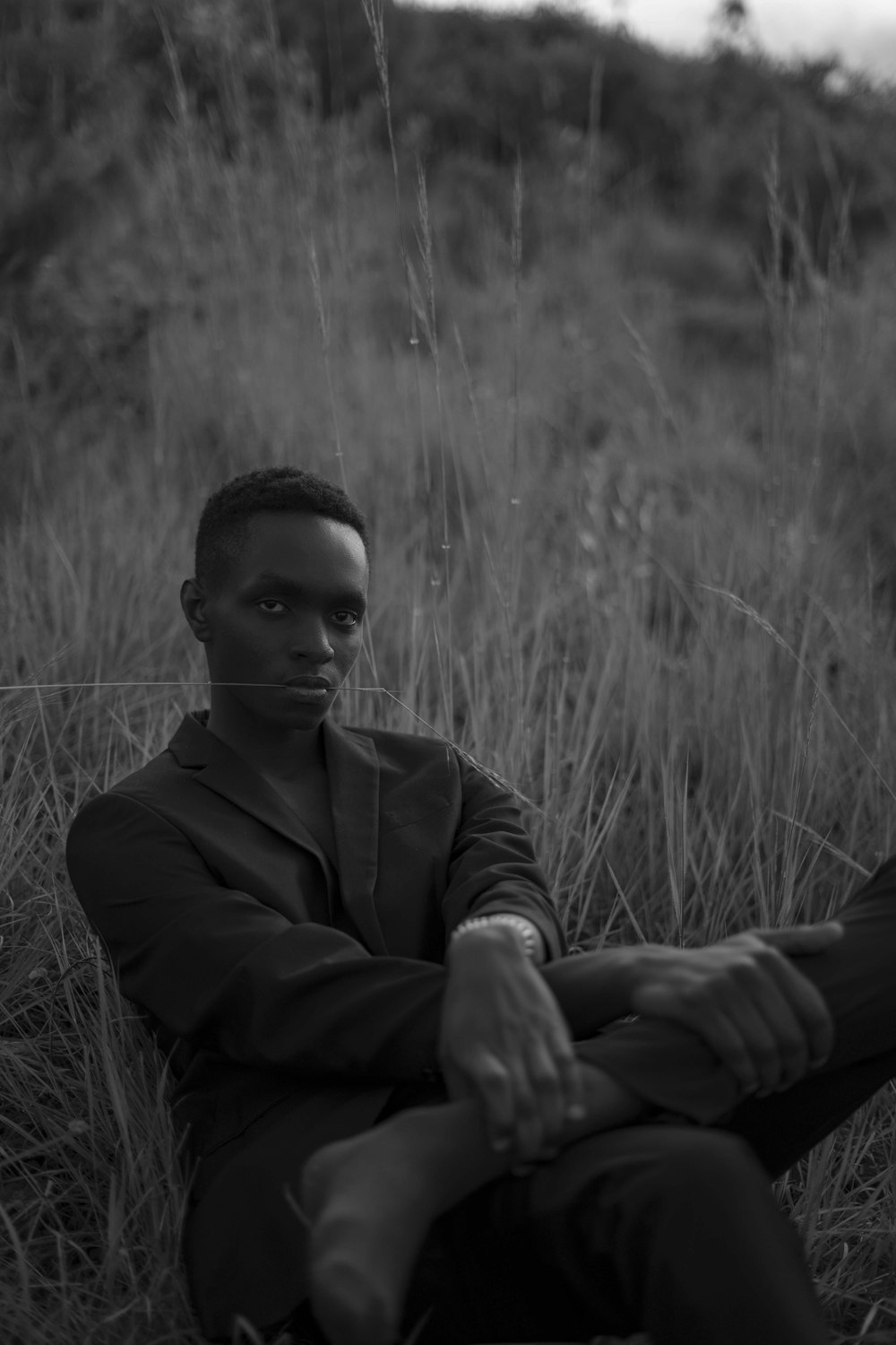 a black and white photo of a man sitting in a field