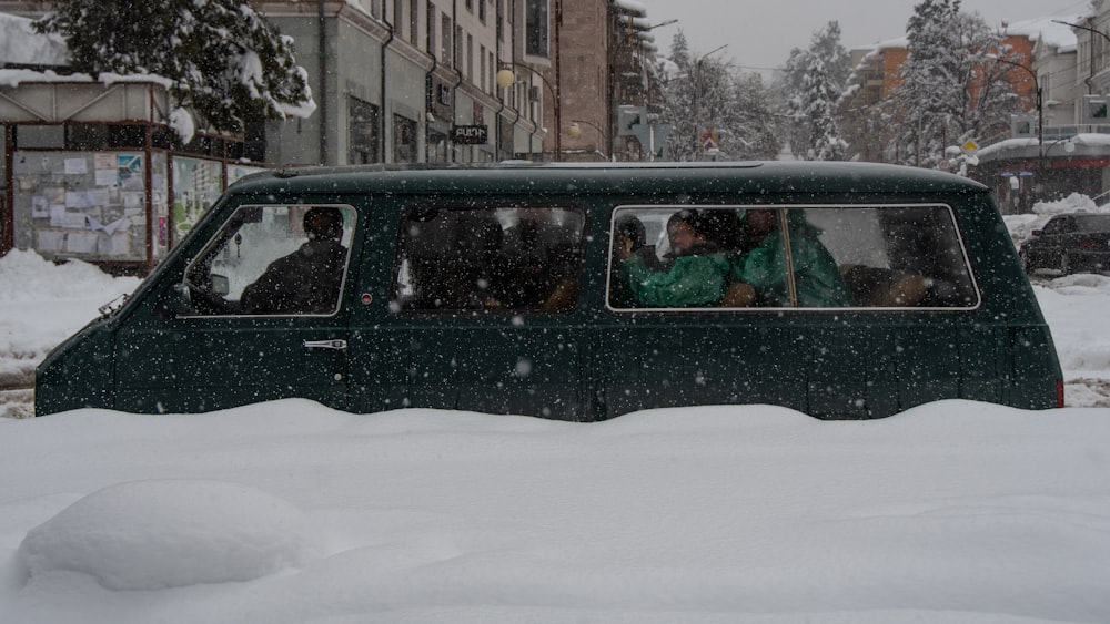 a group of people in a green vehicle in the snow