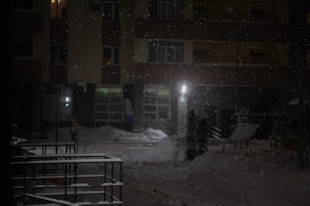 a snow covered street at night with a building in the background