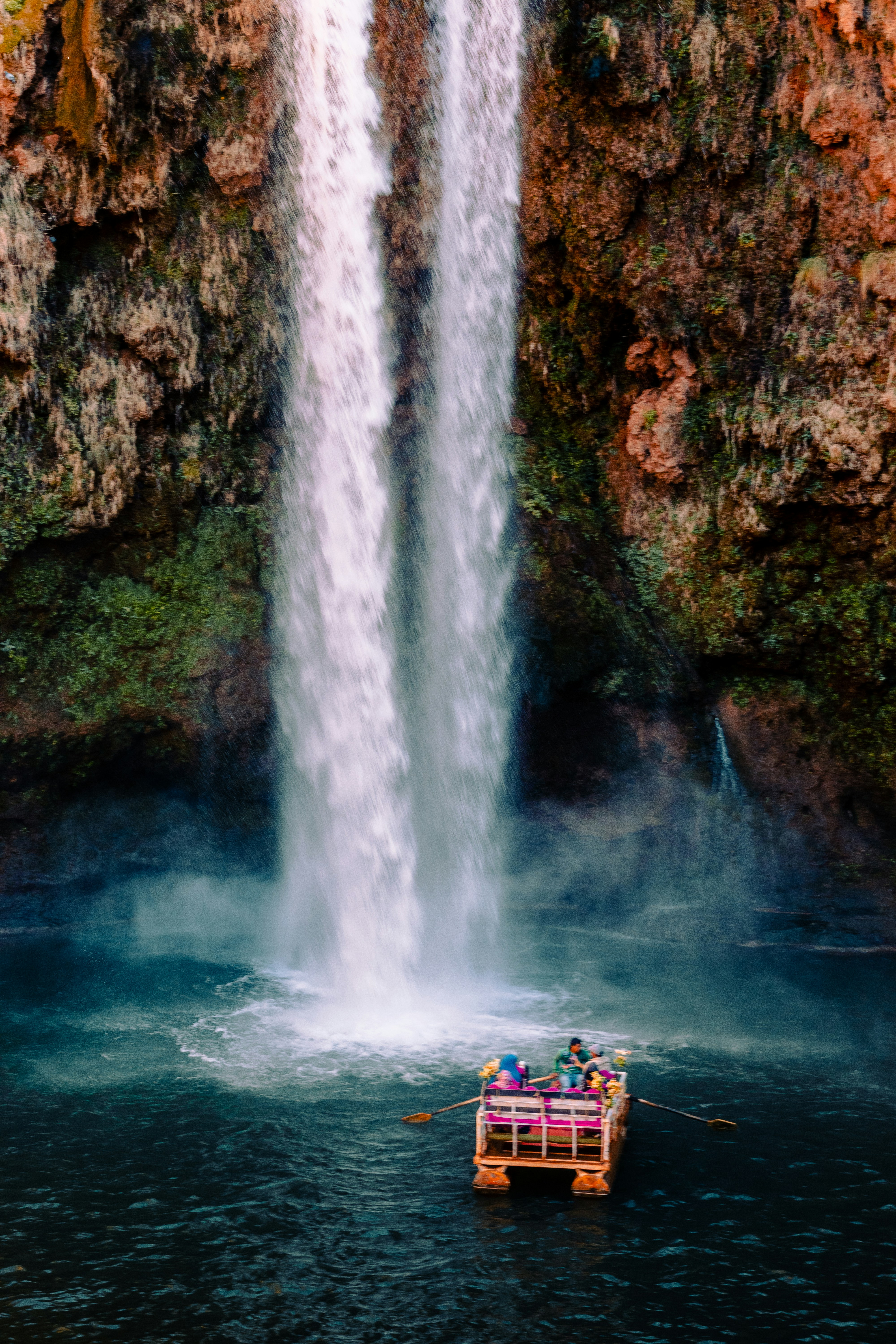A boat floating in a body of water near a waterfall photo – Free Nature ...