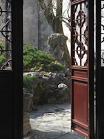 Traditional wooden doors opening to a peaceful garden path.