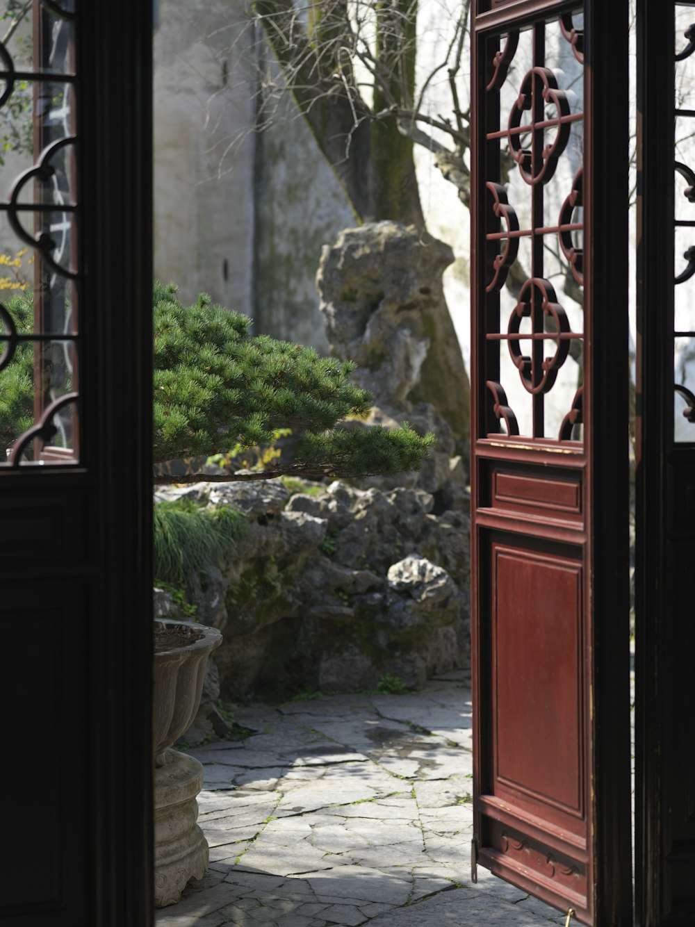 an open door leading to a garden with rocks and trees