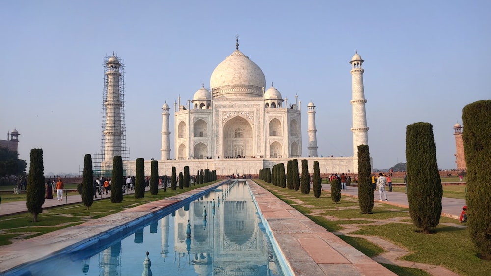 a large white building with a long pool in front of it