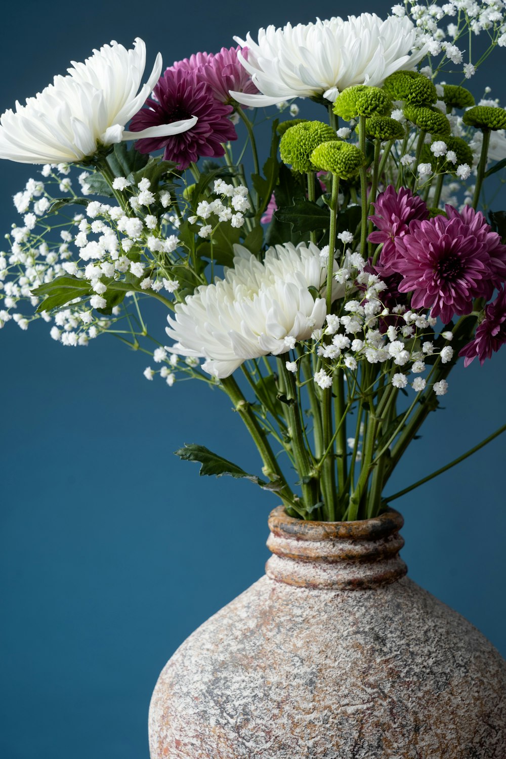 a vase filled with lots of white and purple flowers
