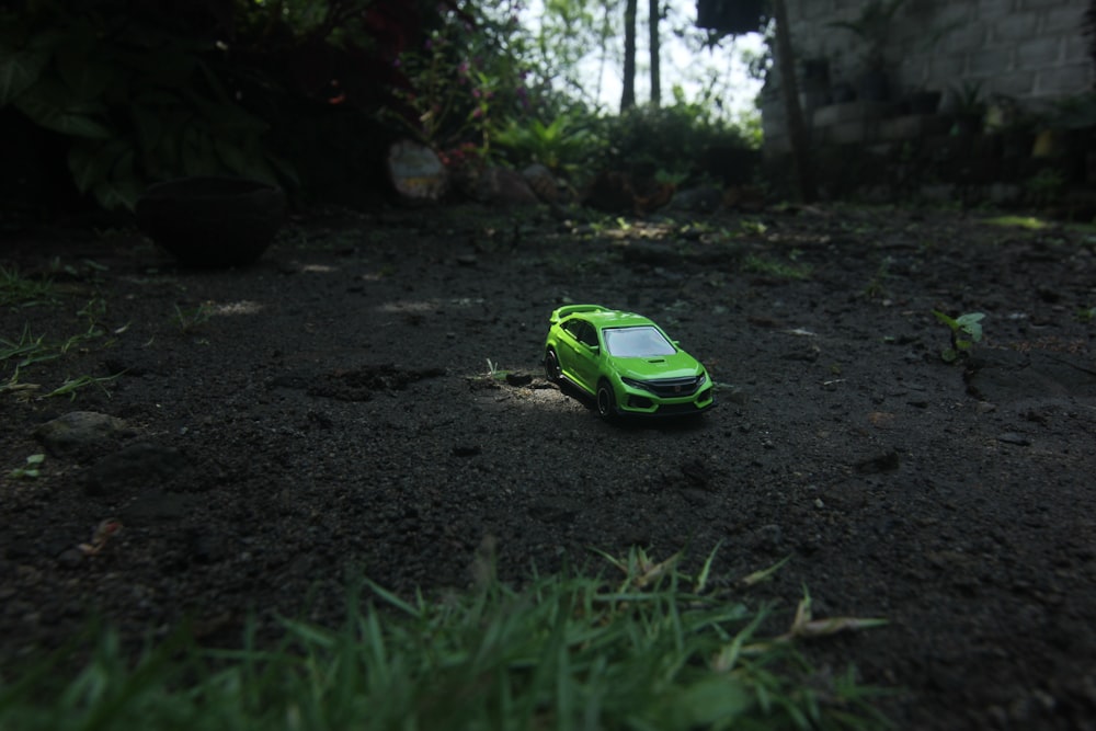 a toy car sitting in the middle of a dirt road